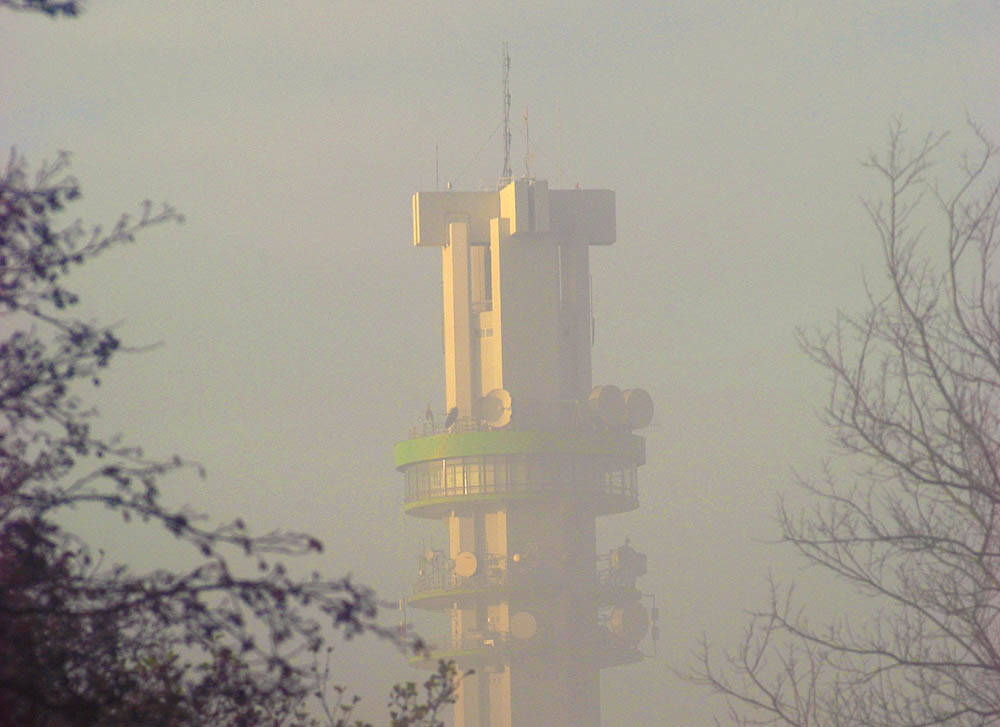 Terwijl de top van de KPN-straalverbindingstoren in Spannenburg in de zon staat te schitteren, is het ondereind in nevelen gehuld. De mist reikt niet hoger dan enkele tientallen meters. De toren zelf is 118 meter hoog en zorgt voor de verbinding van onder andere telefoonverkeer.