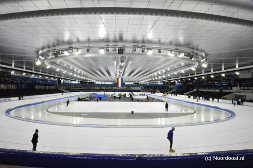 De vierhonderdmeterbaan van ijsstadion in Thialf baadt in een zee van licht. De lampen hangen aan het plafond.