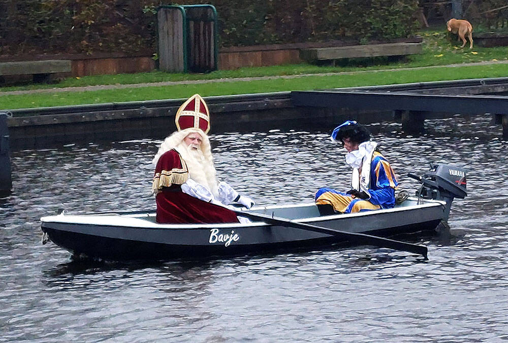 Intocht van Sinterklaas in Langweer. De goedheiligman roeit zelf in een stalen bootje de oude dorpshaven binnen.