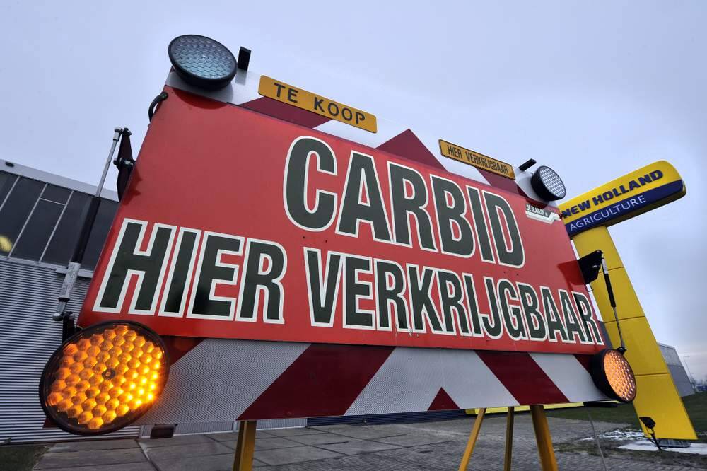 Met een opvallend omgebouwd verkeersbord prijst De Blaauw Mechanisatiebedrijven in Sneek zijn handel in carbid aan. Normaliter verkoopt het bedrijf trekkers en landbouwwerktuigen, maar rond de jaarwisseling zit ook carbid in het assortiment. Het carbidschieten met melkbussen levert oorverdovende knallen en wordt vooral op het platteland bedreven. Het carbid wordt in de melkbus gedaan, wat water erbij en er wordt gas gevormd. Een fakkel bij het gaatje in de bodem van de melkbus zorgt voor de ontbranding van het gas. Oordoppen of andere gehoorbeschermers zijn verplichte nummers vanwege de loeiharde knallen.