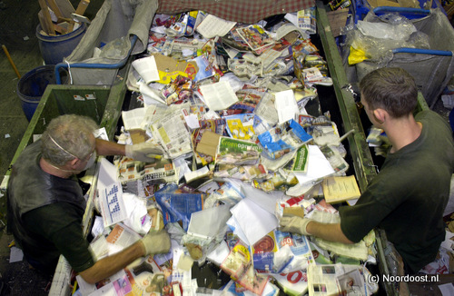 Heesch - Twee medewerkers van van Munster Recycling bv uit Heesch sorteren oud papier.